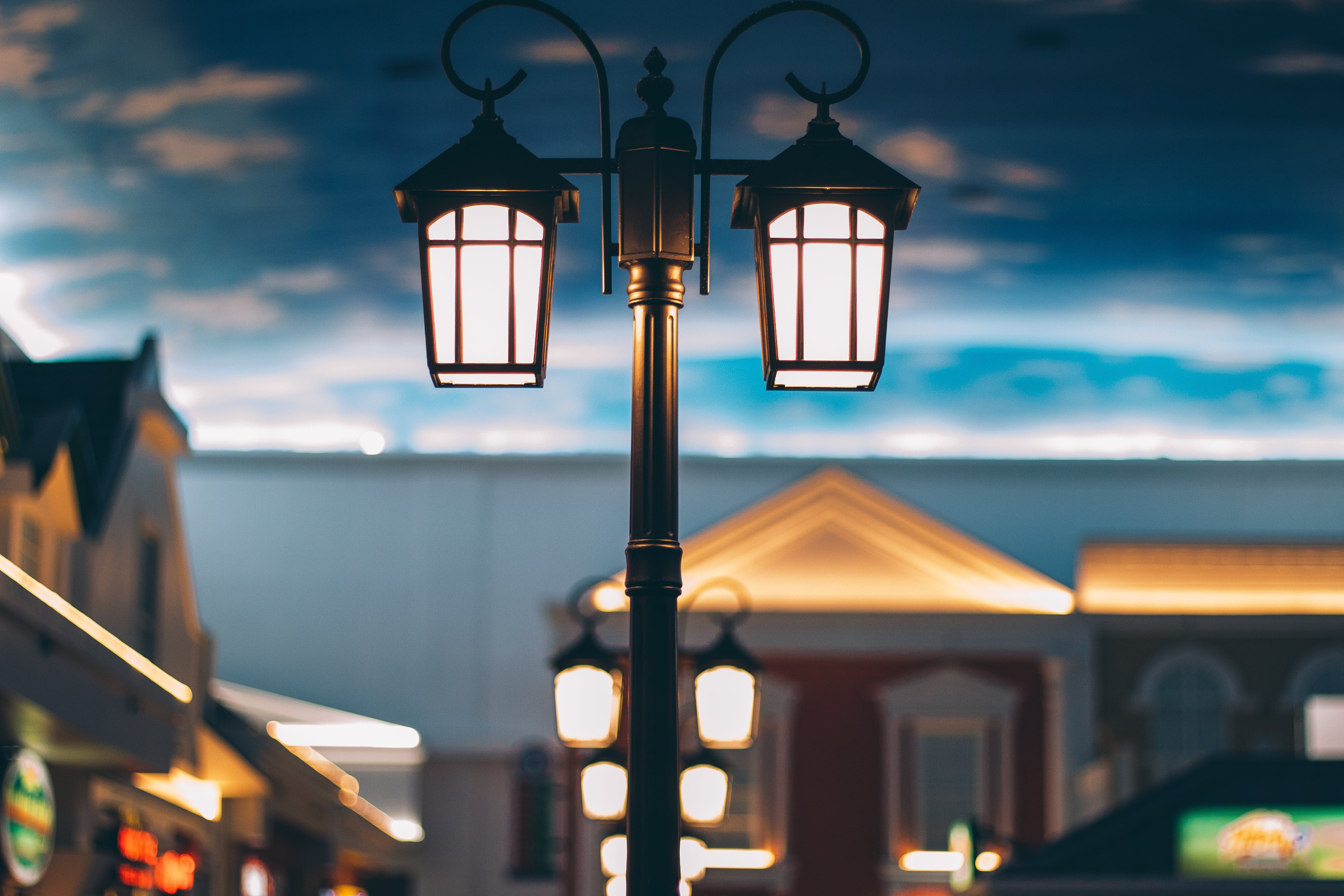 A street lamp illuminates the place with clouds behind it at dawn